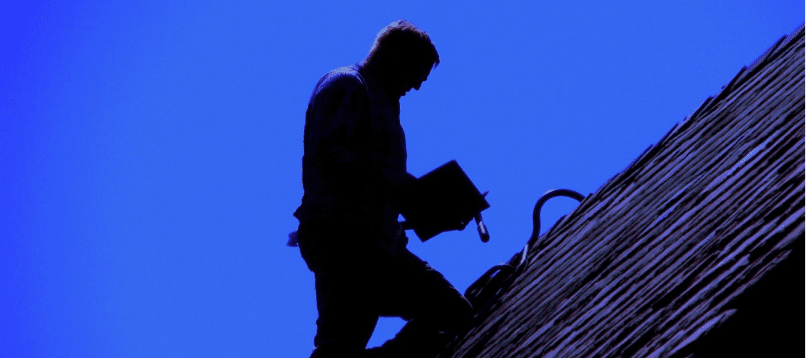 A man is standing on the roof of his house