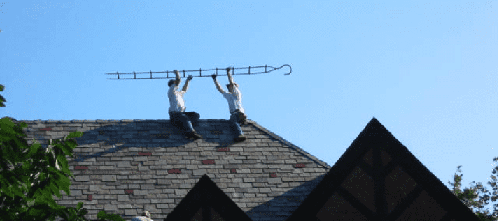 Two men are on a roof with a ladder.