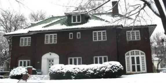 A large brown house with snow on the roof.